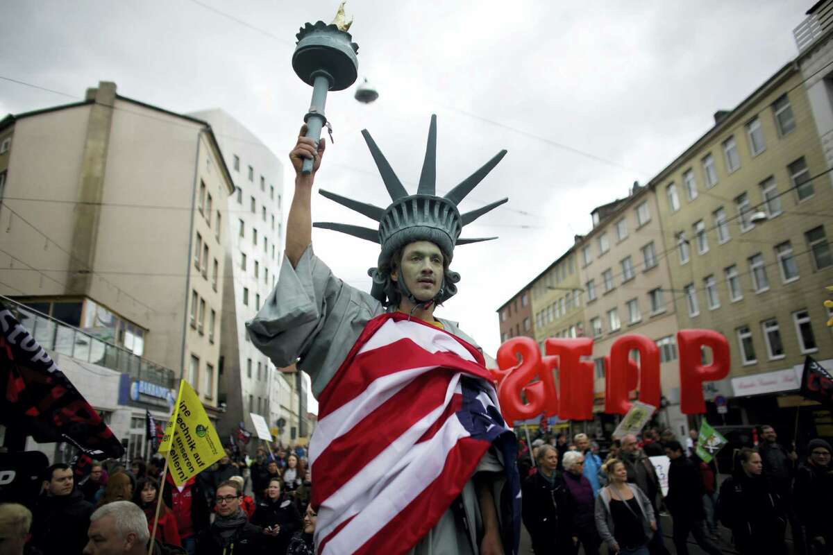In this April 23, 2016 picture, a man walking on stilts and dressed like the Statue of Liberty attends a protest against the planned Transatlantic Trade and Investment Partnership, or TTIP, ahead of the visit of United States President Barack Obama in Hannover, Germany.