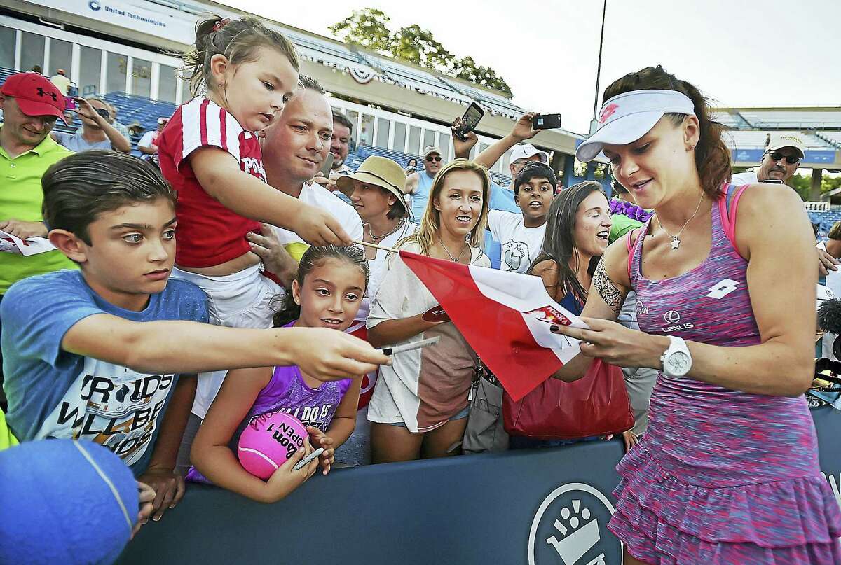 Poland’s Agnieszka Radwanska autographs a Polish flag after defeating Ukraine’s Elina Svitolina in the championship match at the Connecticut Open on Saturday.