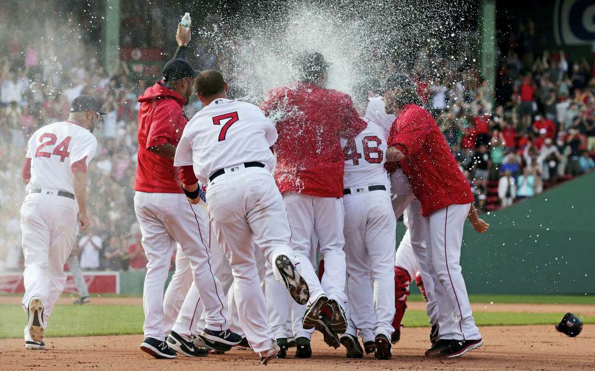 Teammates surround Boston Red Sox’s Xander Bogaerts and douse him after his walkoff RBI-single during the 10th inning against the Chicago White Sox at Fenway Park Thursday in Boston.