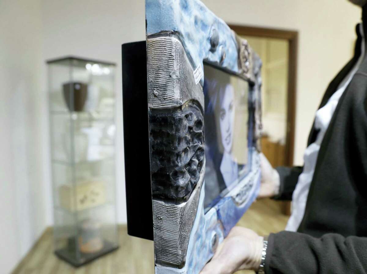 A man holds an urn in the shape of a picture frame at a funeral parlor in Rome, Tuesday, Oct. 25, 2016. The Vatican on Tuesday published guidelines for Catholics who want to be cremated, saying their remains cannot be scattered, divvied up or kept at home but rather stored in a sacred, church-approved place.