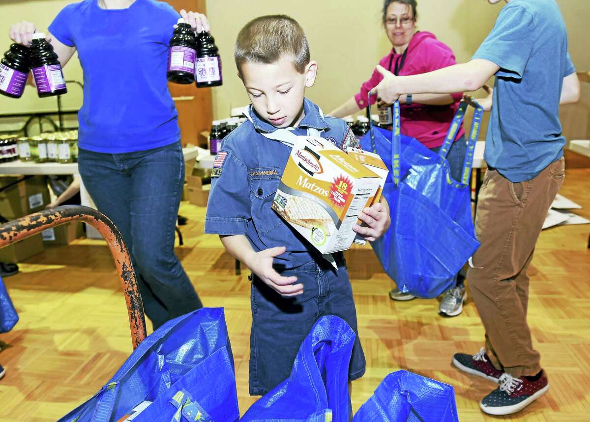 Seth Glassman, 9, of Cub Scout Pack 923 in Orange places boxes of matzo into kosher for Passover food packages for some of over 380 area families at the Jewish Community Center of Greater New Haven in Woodbridge on Sunday. B’nai B’rith International organizes Project H.O.P.E. (Help Our People Everywhere) to deliver Passover food to poor and elderly Jews in several Northeastern states.