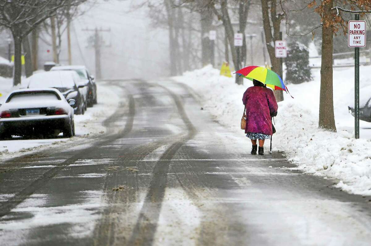 A woman walks in the snowfall down Bradley Avenue in Branford Monday. Schools in Branford were set to open 90 minutes late Tuesday as the town cleaned up from the latest storm.
