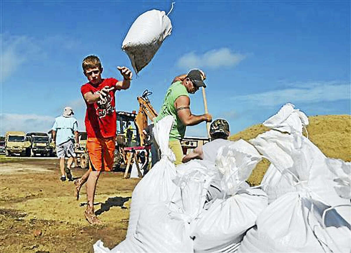 Young Dylan Heinan, among other volunteers, piles sandbags in an effort to stop flood waters from rising in Lake Arthur, La., Wednesday, Aug. 17, 2016.