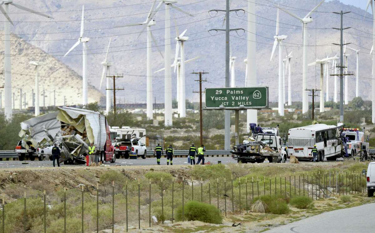 Tow truck drivers prepare to haul away a tour bus that crashed with a semi-truck on Interstate 10, west of the Indian Canyon Drive off-ramp, in Desert Hot Springs, near Palm Springs, Calif., Sunday, Oct. 23, 2016. The tour bus and the semi-truck crashed on the highway in Southern California early Sunday, killing at least 11 people and injuring at least 30 others, some critically, the California Highway Patrol said.