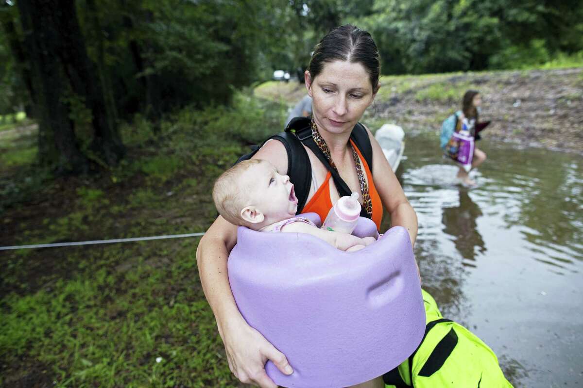 Danielle Blount carries her 3-month-old baby, Ember, to a truck from the Louisiana Army National Guard as they evacuate the area near Walker, La., after heavy rains inundated the region, Sunday, Aug. 14, 2016.