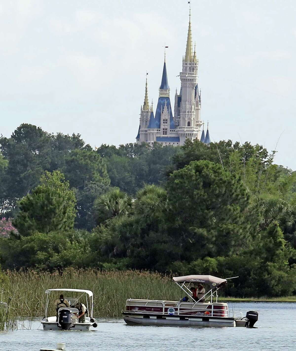 In the shadow of the Magic Kingdom Florida Fish and Wildlife Conservation Officers search for the body of a young boy Wednesday, June 15, 2016 after the boy was snatched off the shore and dragged underwater by an alligator Tuesday night at Grand Floridian Resort at Disney World in Lake Buena Vista, Fla.