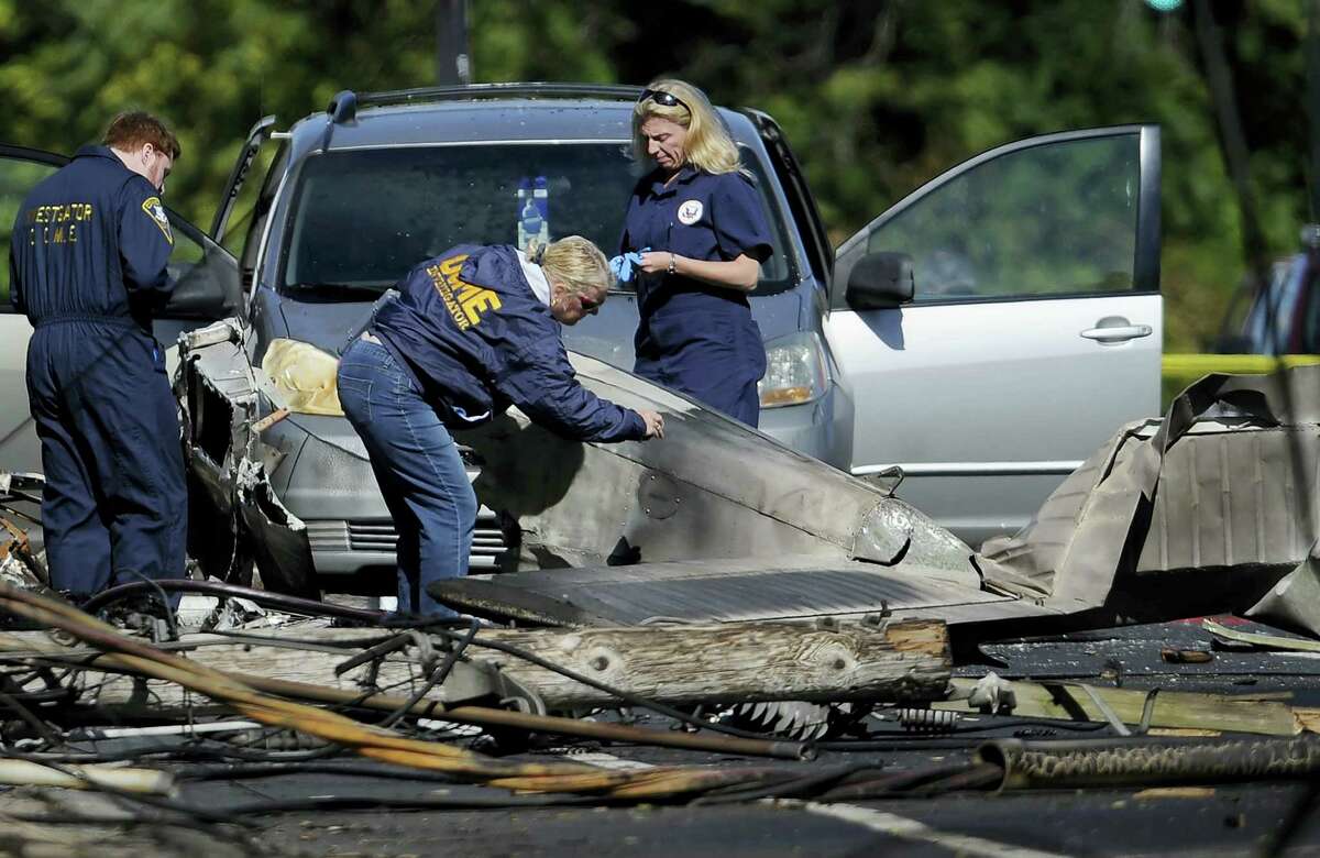 Investigators look at the remains of a small plane along Main St. in East Hartford a day following the plane’s crash.