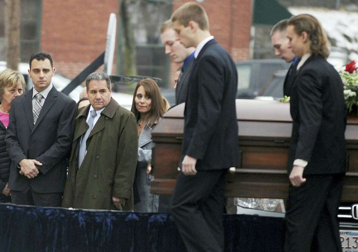 In this Dec. 30, 2015 photo, Richard Dabate, left, watches the casket bearing his late wife Connie Dabate being carried during her funeral outside St. Bernard Roman Catholic Church in Vernon. While responding to a burglary alarm on Dec. 23, authorities found Connie Dabate, mother of two children, shot to death and her husband Richard Dabate injured inside their Ellington home. No arrests have been made, leaving local residents concerned and speculating.