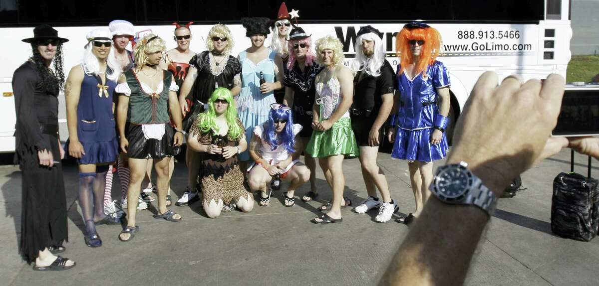 Oakland Athletics rookie players dressed in costumes line up for a group photo before boarding the team bus.