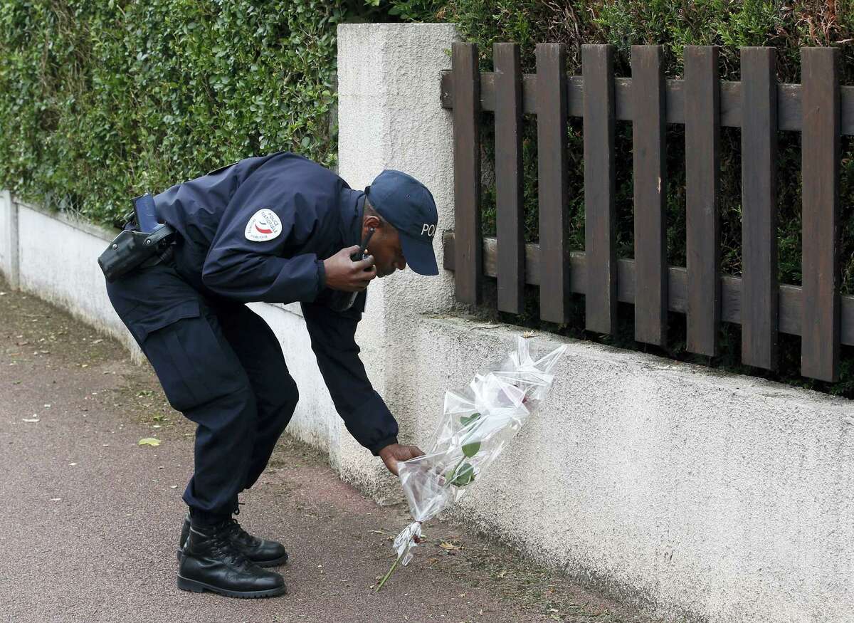 A French police officer lays flowers while paying tribute to his colleagues killed in a knife attack near their home in Magnanville, west of Paris, France, Tuesday, June 14, 2016. French President Francois Hollande says the stabbing attack that left two police officials dead was “incontestably a terrorist act.”