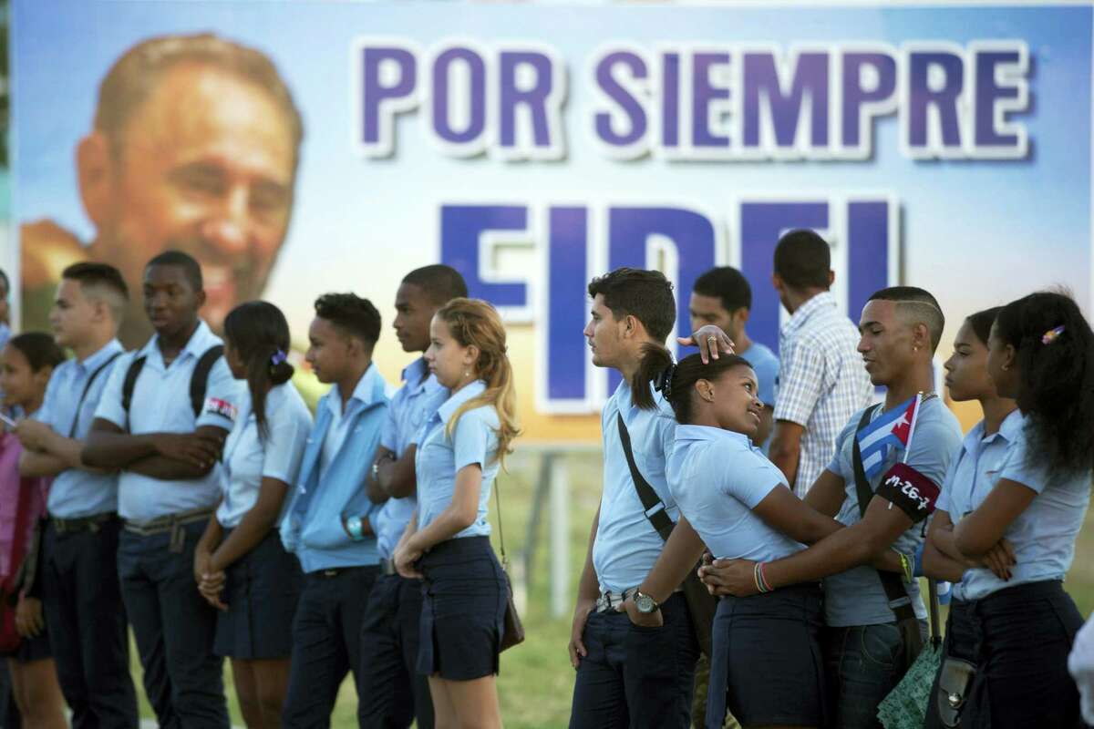 Students wait to see the ashes of Cuba’s leader Fidel Castro driven to the Santa Ifigenia cemetery in Santiago, Cuba, Sunday, Dec. 4, 2016. The motorcade carrying the ashes made i’s final journey towards the cemetery as thousands of people lined the short route from the Plaza Antonio Maceo.(AP Photo/Ricardo Mazalan)