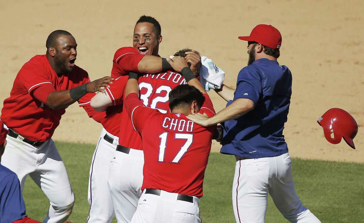 The Rangers’ Josh Hamilton (32) is mobbed by teammates after his two-run walkoff double during the ninth inning on Sunday.