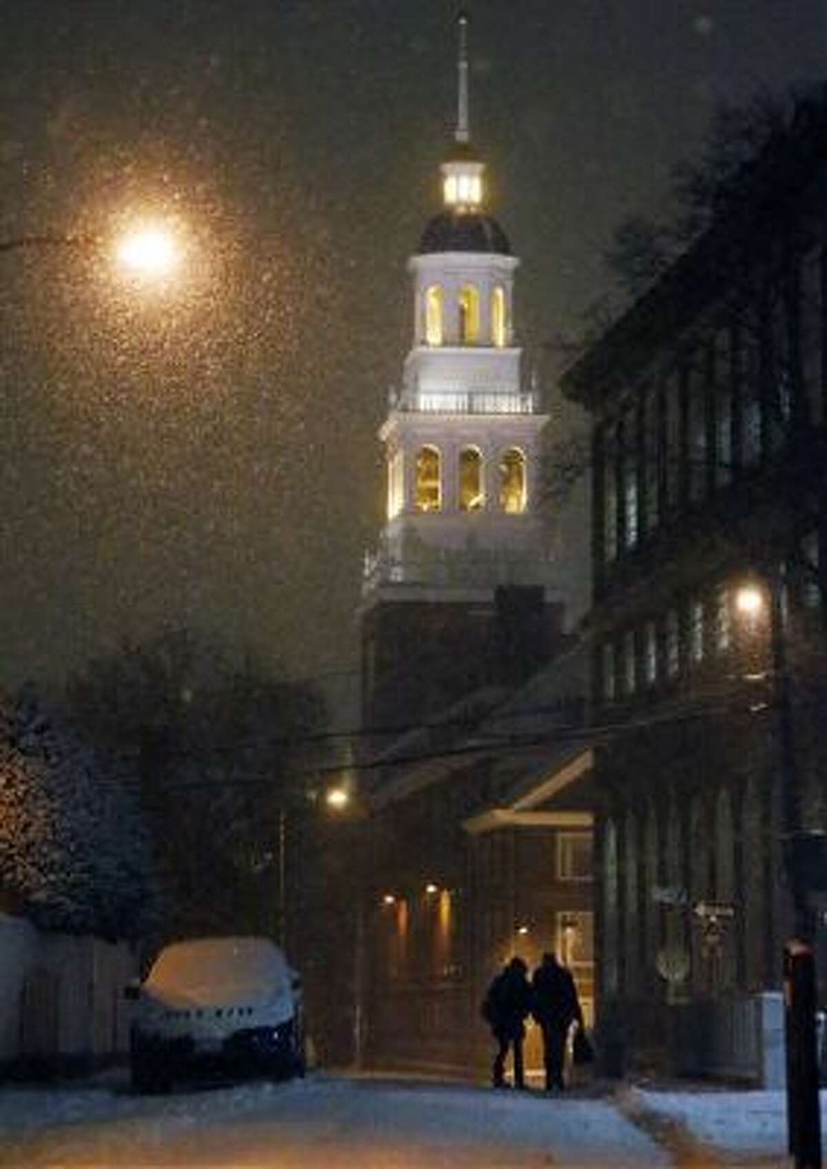 A couple walk as snow falls in Harvard Square in Cambridge, Mass., on Tuesday.