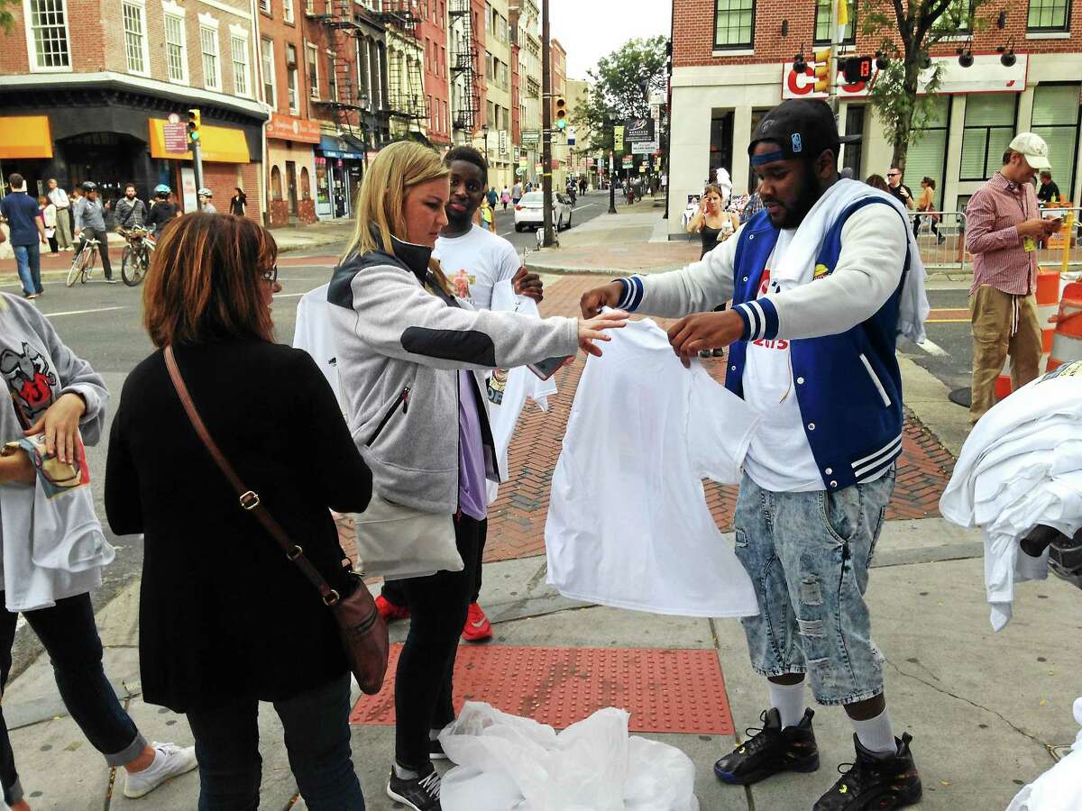 Caitlyn Cummings buys a pope shirt from street merchant Zac Coumbassa near 3rd and Market during Pope Francis’ visit to Philadelphia.