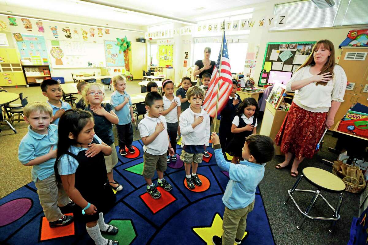 In this April 30, 2014 photo, children in Erin Kling's, right, pre-kindergarten class recite the Pledge of Allegiance at the start of the school day at Stafford Elementary School in Tacoma, Wash. The U.S. Department of Education announced in early April that Washington was losing its waiver from the restrictions of the No Child Left Behind law, which will cause state school districts to lose their say in how about $40 million in formerly flexible funding is used for education, including the formation of two pre-K classes at Stafford. (AP Photo/Ted Warren)