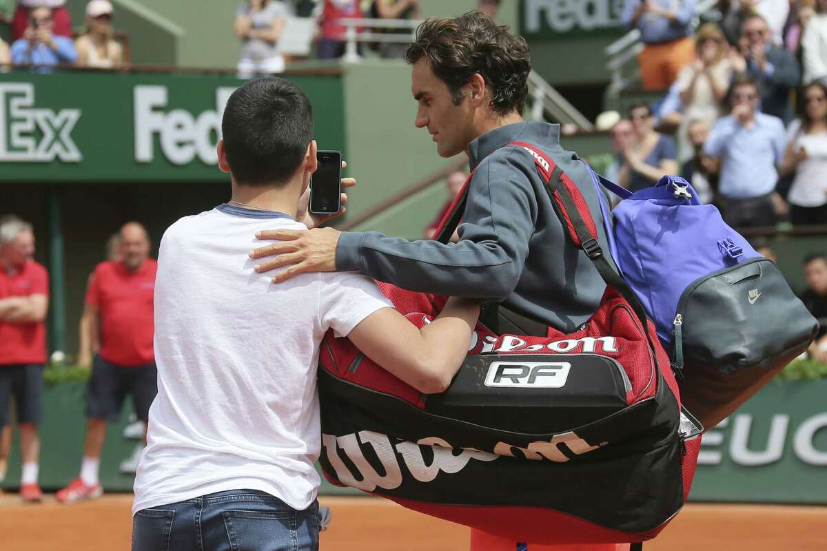 A boy who climbed down from the stands takes a selfie with Switzerland’s Roger Federer in the first round match of the French Open on Sunday.