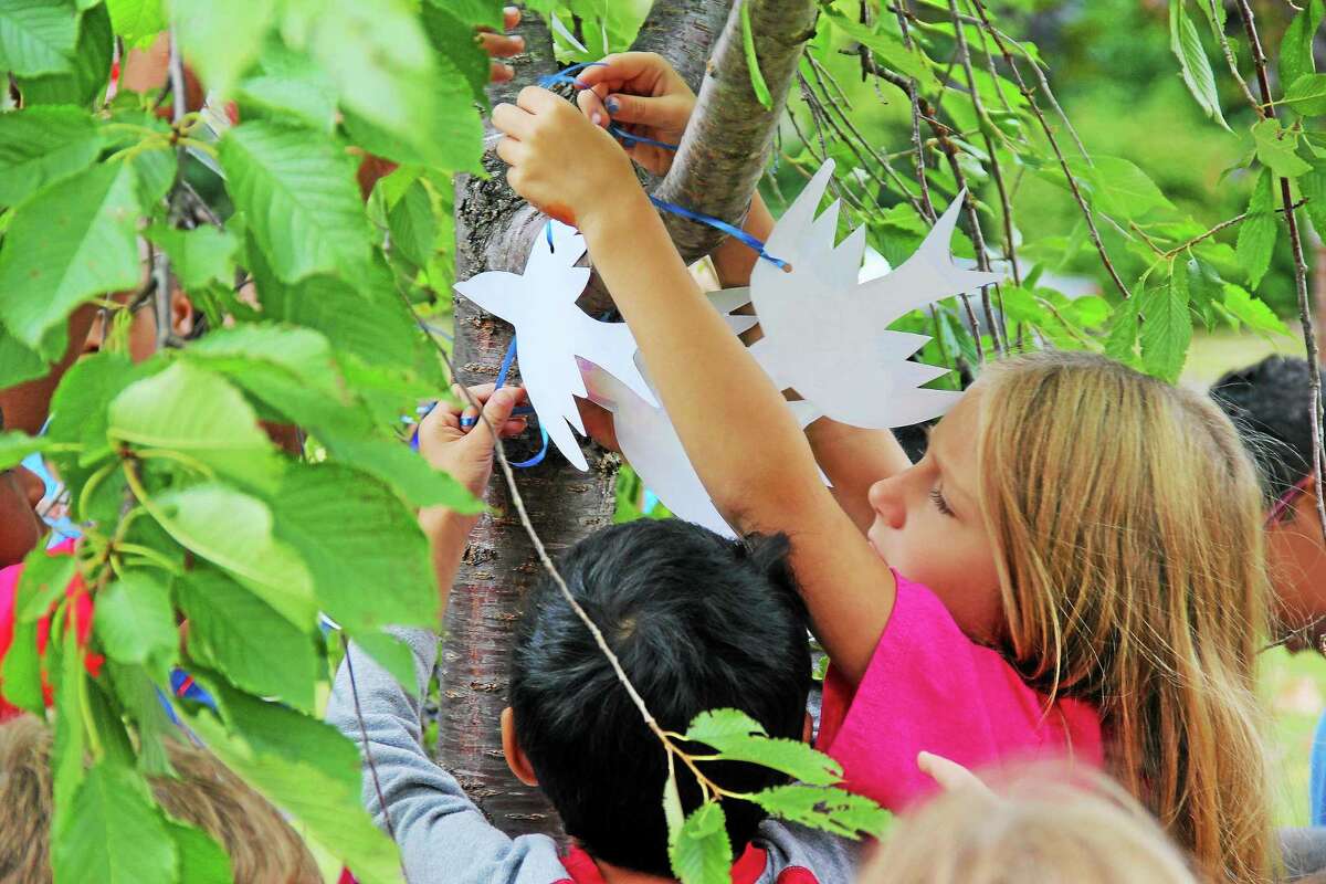 Peace doves fly at Farm Hill School on the 13th anniversary of Sept. 11 as second-graders decorate a memorial tree in front of the school. School librarian Lori Petras and first-year teacher Stacie Eagleson, daughter-in-law of the late Bruce Eagleson who died in the 2001 terrorist attacks, organized a brief ceremony to remember the lives lost.