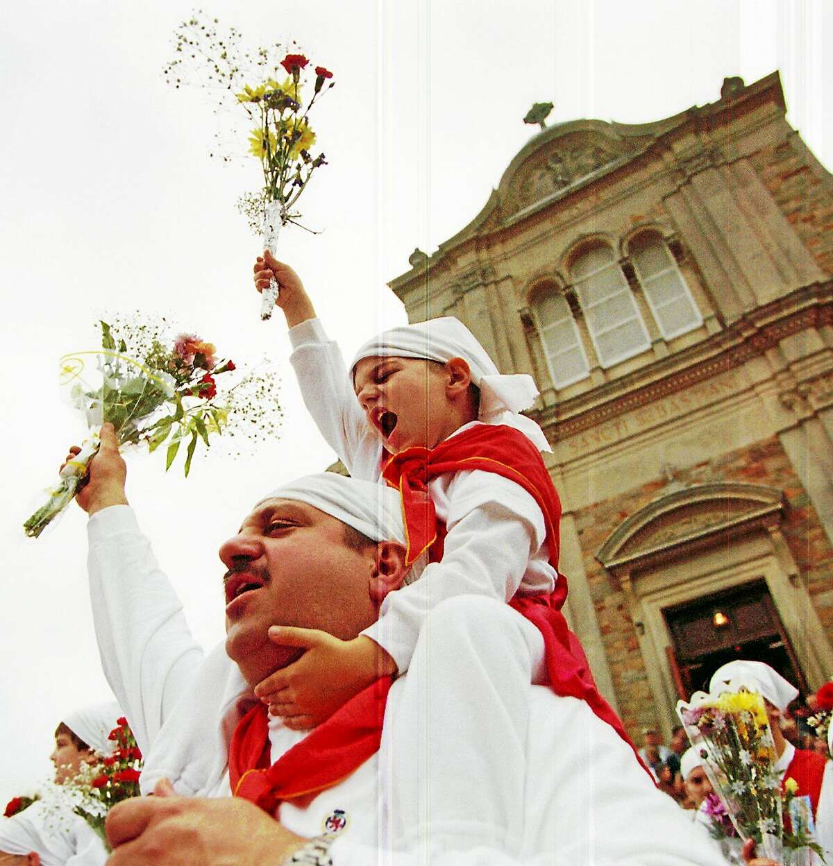 In this 2000 file photograph, Marcus Fazzino rides high on his father Nick’s shoulders as they stream out of St. Sebastian’s Church shouting, “prima diu e sammastianu” during the celebration of the Feast of St. Sebastian.