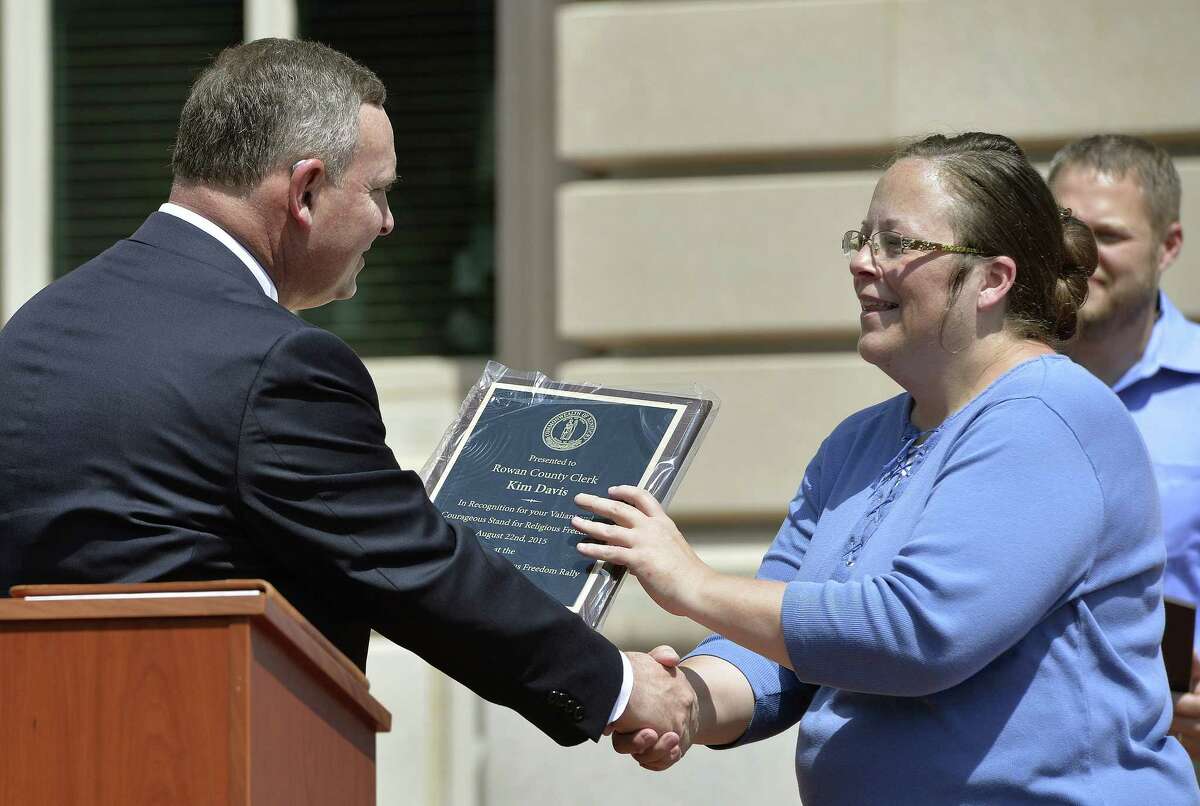 Pastor Jeffrey Fugate of the Clays Mill Road Baptist Church in Lexington, Ky., left, gives an award to Rowan County Clerk Kim Davis during a Religious Freedoms Rally at the Kentucky State Capitol in Frankfort Ky., Saturday, Aug. 22, 2015. Davis has been sued by The American Civil Liberties Union for denying marriage licenses to same-sex couples. She says her Christian faith prohibits her from signing the licenses.