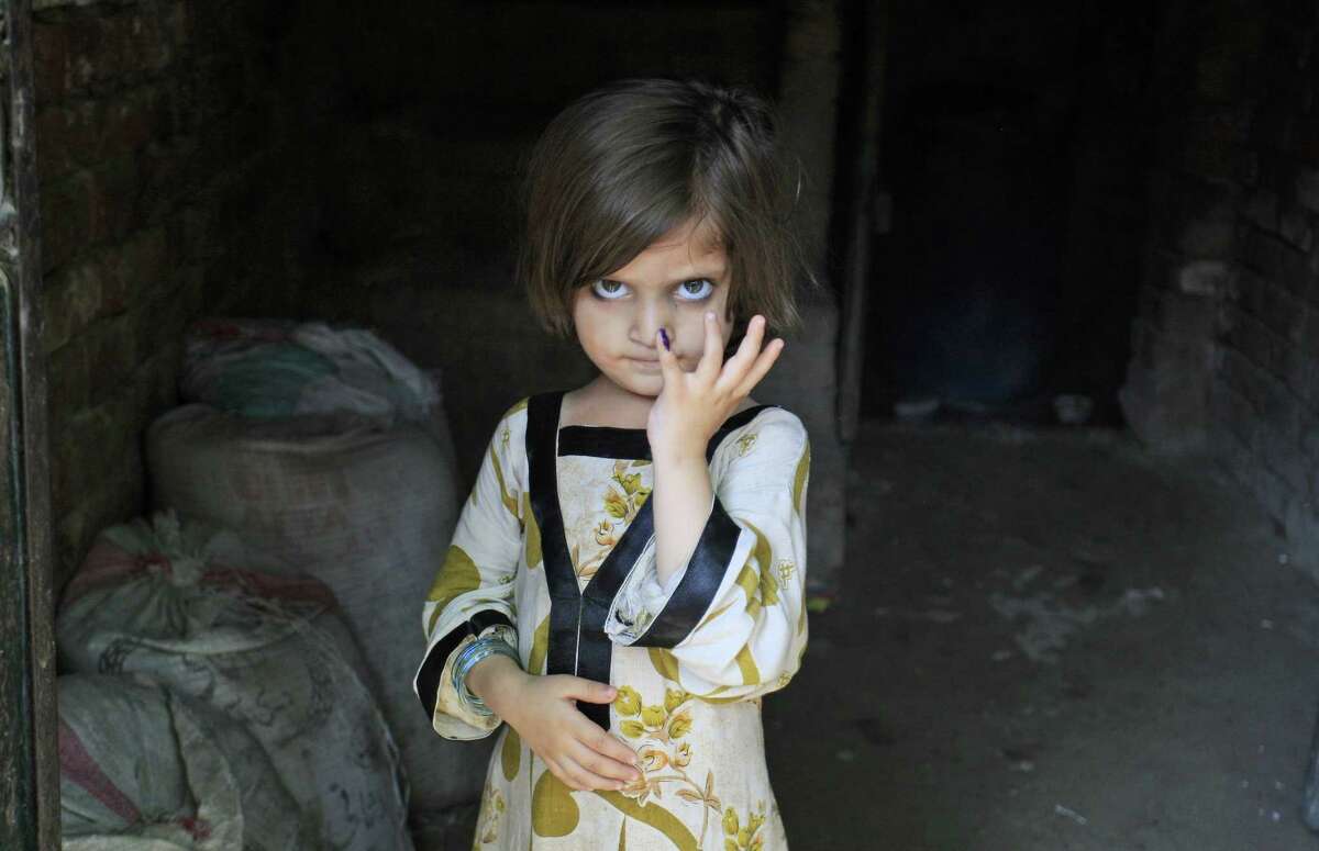 A Pakistani girl shows her finger marked with ink after receiving a polio vaccine from a health worker in Lahore, Pakistan, in this 2012 photo.