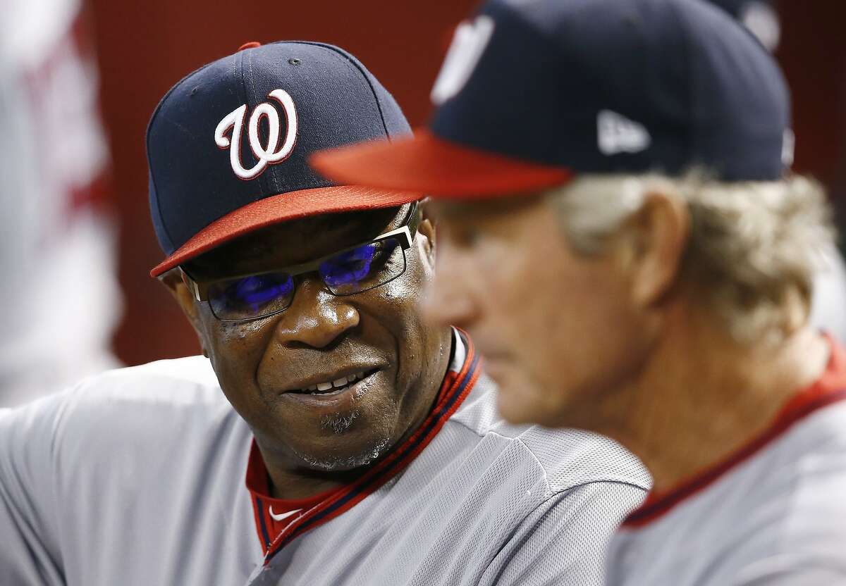 Washington Nationals manager Dusty Baker, left, talks with bench coach Chris Speier in the dugout prior to a baseball game against the Arizona Diamondbacks Sunday, July 23, 2017, in Phoenix. The Nationals defeated the Diamondbacks 6-2. (AP Photo/Ross D. Franklin)