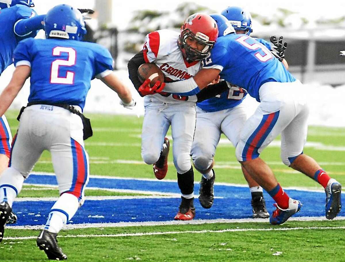 A Cromwell running back battles through Coginchaug defenders during last year’s Thanksgiving Day matchup. Cromwell and Portland players, now playing as a combined team, are being investigated for possible locker room hazing.