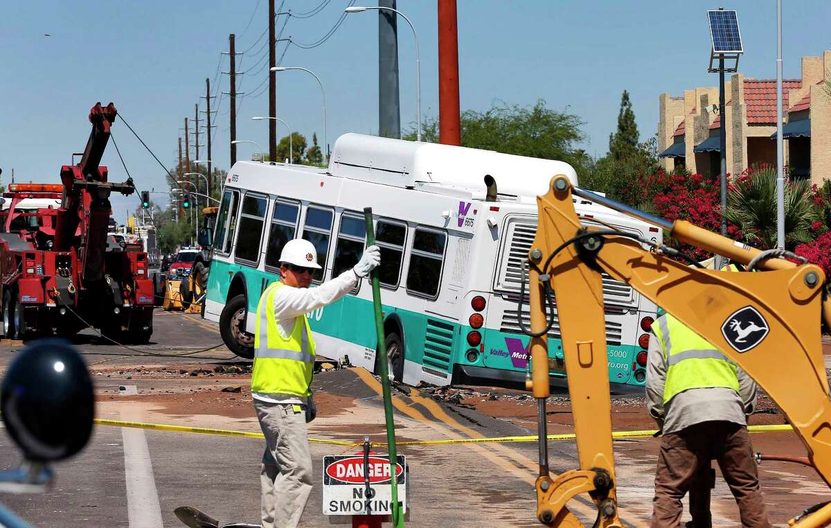 A valley metro bus sits mired in a collapsed, muddy street after a water main break flooded the area, Wednesday, Sept. 3, 2014 in Tempe, Ariz.