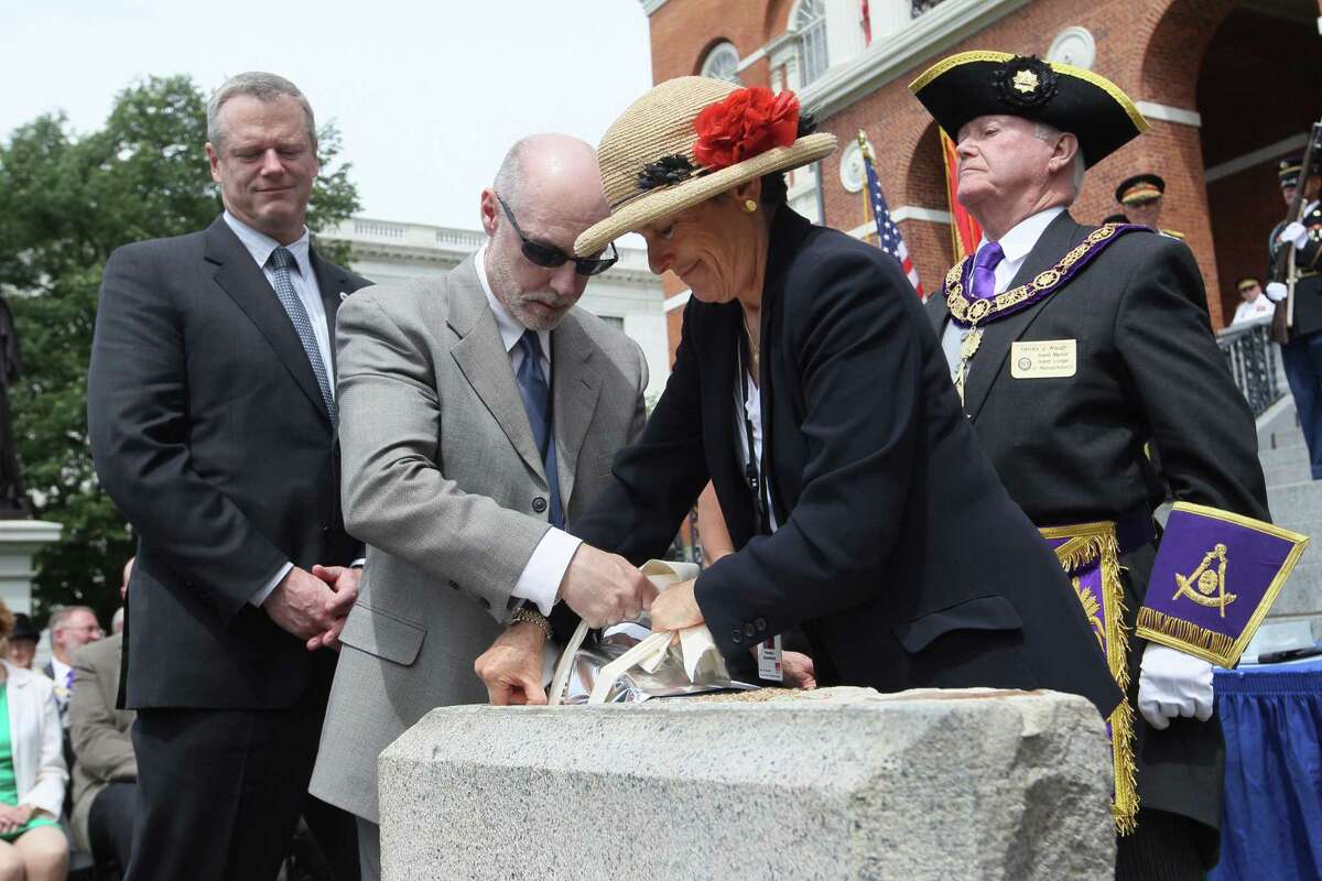 Massachusetts Gov. Charlie Baker, left, watches as State Arcivist Michael Comeau amd MFA head of Objects Conservation Pamela Hatchfield lower the time capsule into the cornerstone during a ceremony at the Statehouse in Boston, Wednesday, June 17, 2015. At right, is Grand Master of Grand Lodge of Masons Harvey Waugh. The time capsule was returned to cornerstone during ceremony at the Statehouse steps. A a set of 2015 U.S. mint coins and a silver plaque added to its contents for a future generation to discover. (Joanne Rathe/The Boston Globe via AP, Pool)