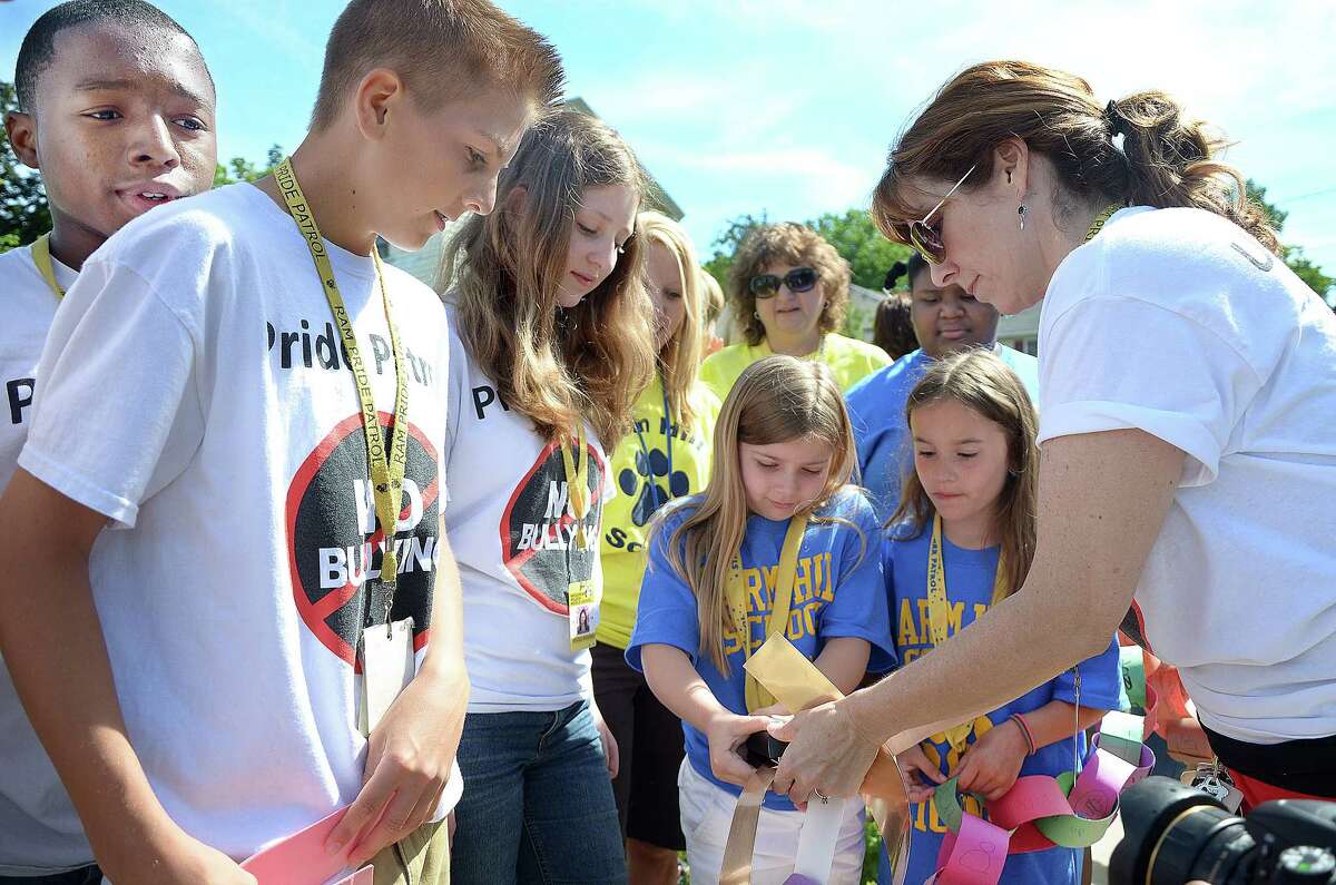 Co-advisor for the Woodrow Wilson Middle School Pride Patrol Monique Nee lends a hand to Meredith Latronica, 8, a member of the STAR Patrol at Farm Hill Elementary School who connects the paper links from Farm Hill School to the links from the Ram Pride Patrol at WWMS on Newtown Street in Middletown. The connecting links carry the anti-bullying message, “If It’s MEAN, INTERVENE.” Looking on are members from the WWMS Pride Patrol, Jay Hoggard, 14, Carson Fitzner, 13, and Nicole Badamo, 14 and Farm Hill’s Caroline Rancourt, 9.