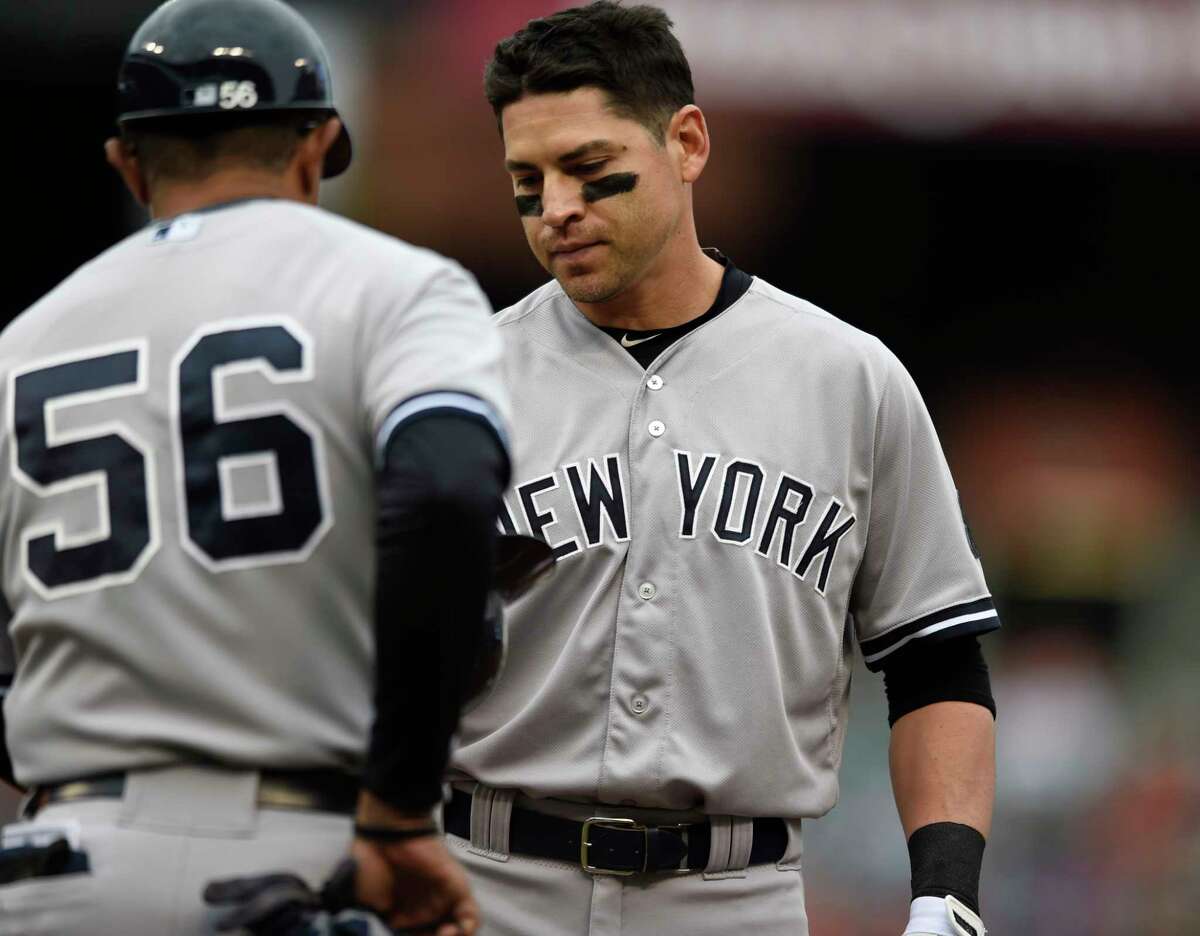 The Yankees’ Jacoby Ellsbury, right, gives his helmet to first base coach Tony Pena after grounding out in the fourth inning Sunday.