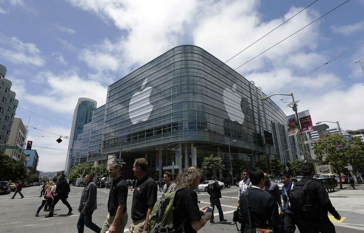 In this June 2, 2014 photo, pedestrians cross the street in front of the Moscone Center, which is hosting the Apple Worldwide Developers Conference, in San Francisco. Apple is expected to announce its new paid streaming-music service at its annual conference for software developers, which kicks off June 8, 2015.