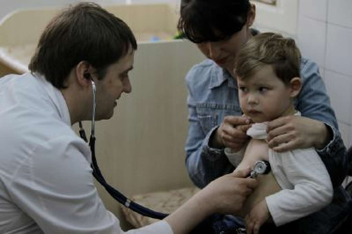 Pediatrician Fyodor Lapiy examines a child before administering him a combined vaccine against diphtheria, whopping cough and tetanus.