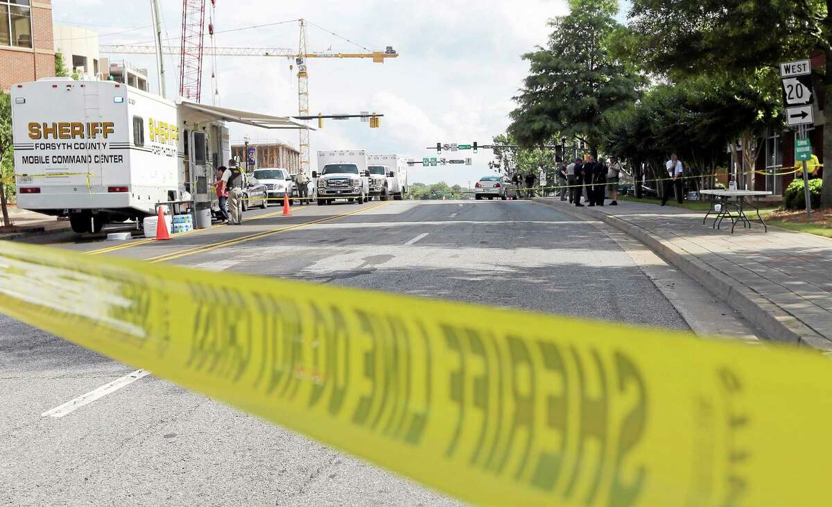 Crime scene tape blocks a road near the Forsyth County Courthouse in Cumming, Ga., on Friday afternoon, June 6, 2014. Earlier Friday, a man wielding an assault rifle, explosives and supplies to take hostages opened fire outside the courthouse, wounding a deputy before he was killed in a shootout with officers, authorities said.