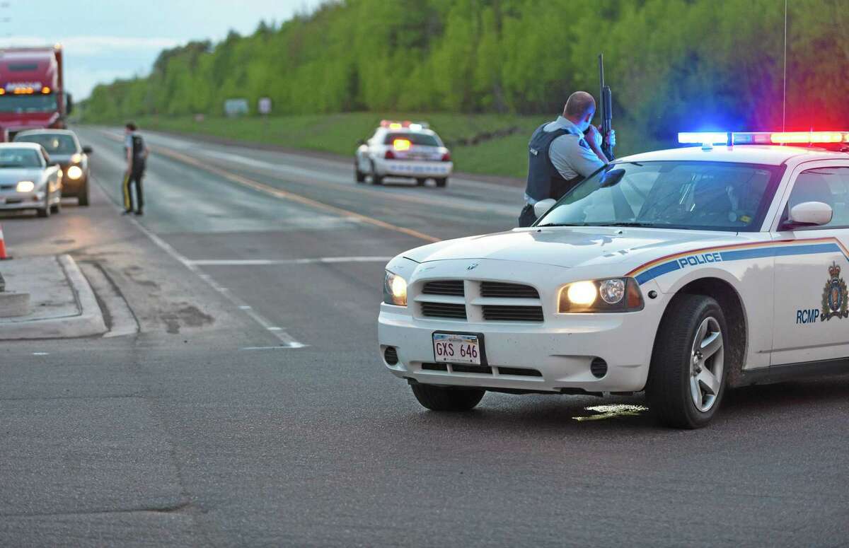 Royal Canadian Mounted Police officers use their vehicles to create a keep a perimeter in Moncton, New Brunswick on Wednesday June 4, 2014. The RCMP in New Brunswick said an undisclosed number of people have been shot and a manhunt is underway in the north end of Moncton for a man armed with guns.