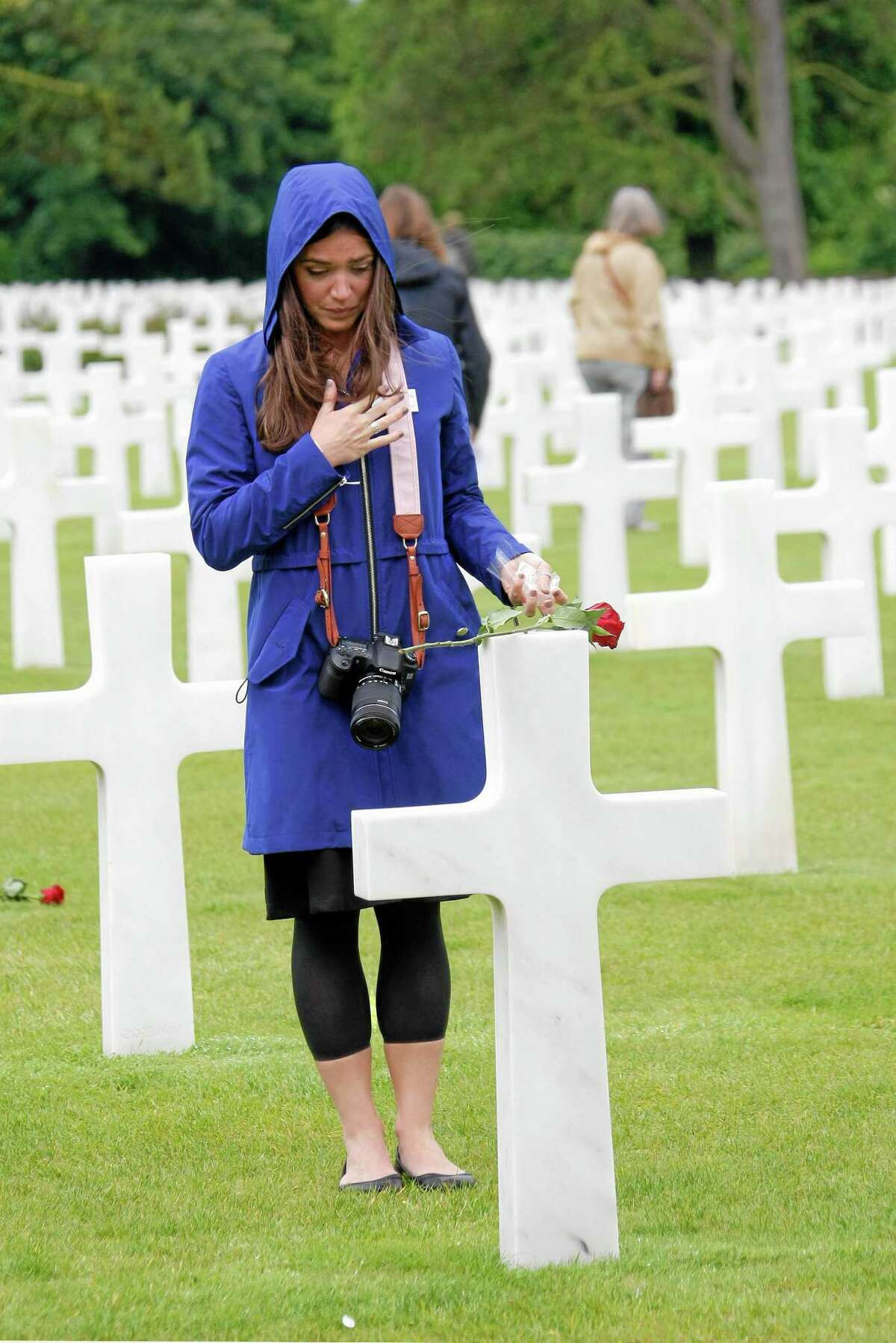 Marissa Neitling, 30, from Lake Oswego, Oregon, places a flower on a grave in the Normandy American Cemetery and Memorial, in Colleville sur Mer, France, June 4, 2014. World leaders and veterans prepare to mark the 70th anniversary of the invasion this week in Normandy. (AP Photo/Claude Paris)
