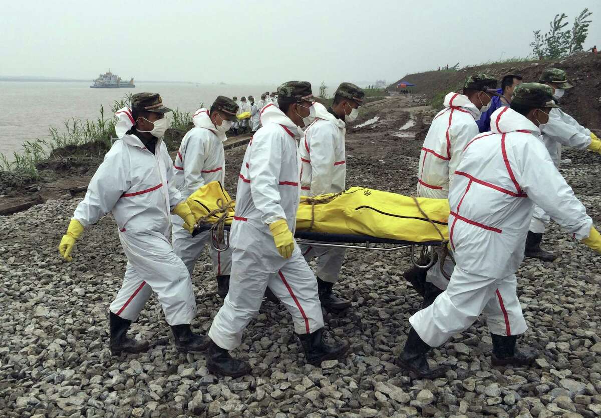 Rescue workers carry a body recovered from a capsized cruise ship in the Yangtze River in Jianli county in southern China's Hubei province Thursday, June 4, 2015. Rescuers cut three holes into the overturned hull of the river cruise ship in unsuccessful attempts to find more survivors Thursday. (Chinatopix Via AP) CHINA OUT