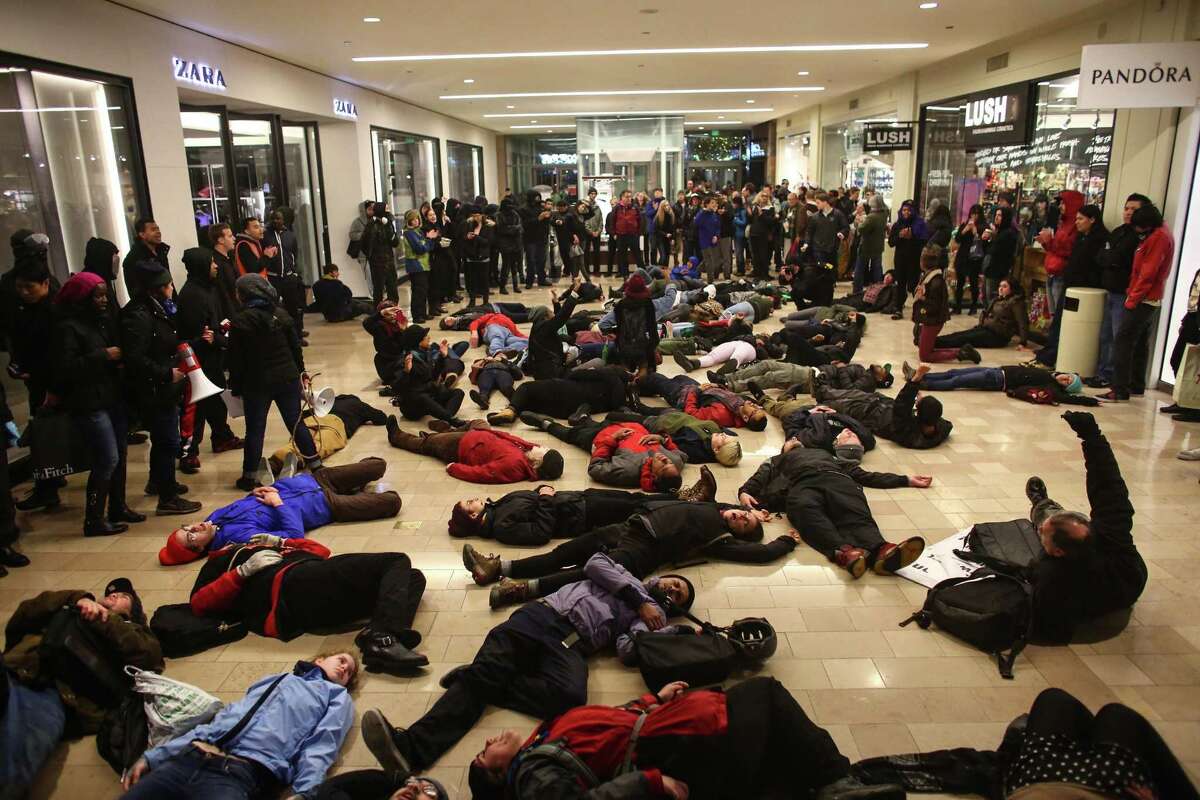 Protestoes gather inside of the Westlake Center in Seattle on Friday, Nov. 28, 2014, to protest a grand jury's decision not to indict a police officer in the shooting of Michael Brown. More than 200 protesters tried to disrupt Black Friday shopping and downtown Seattle's traditional Christmas tree lighting ceremony. Police arrived, arresting several people, and the mall closed early. (AP Photo/seattlepi.com, Joshua Trujillo)