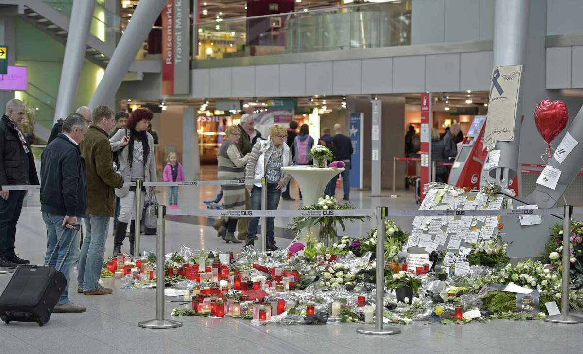 Passengers watch candles and flowers for the victims of the plane crash at the airport in Dusseldorf , Germany on March 31, 2015. One week ago 150 people died in the Germanwings airliner crash in the French alps from Barcelona to Duesseldorf.