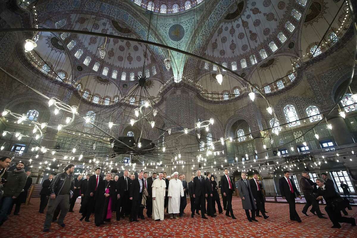 In this photo provided by Vatican newspaper L'Osservatore Romano, Pope Francis and Grand Mufti of Istanbul, Rahmi Yaran visit the Sultan Ahmet mosque in Istanbul, Saturday, Nov. 29, 2014. Meeting with Turkish leaders in the capital Ankara a day earlier, Francis urged Muslim leaders to condemn the "barbaric violence" being committed in Islam's name against religious minorities in Iraq and Syria. (AP Photo/L'Osservatore Romano)