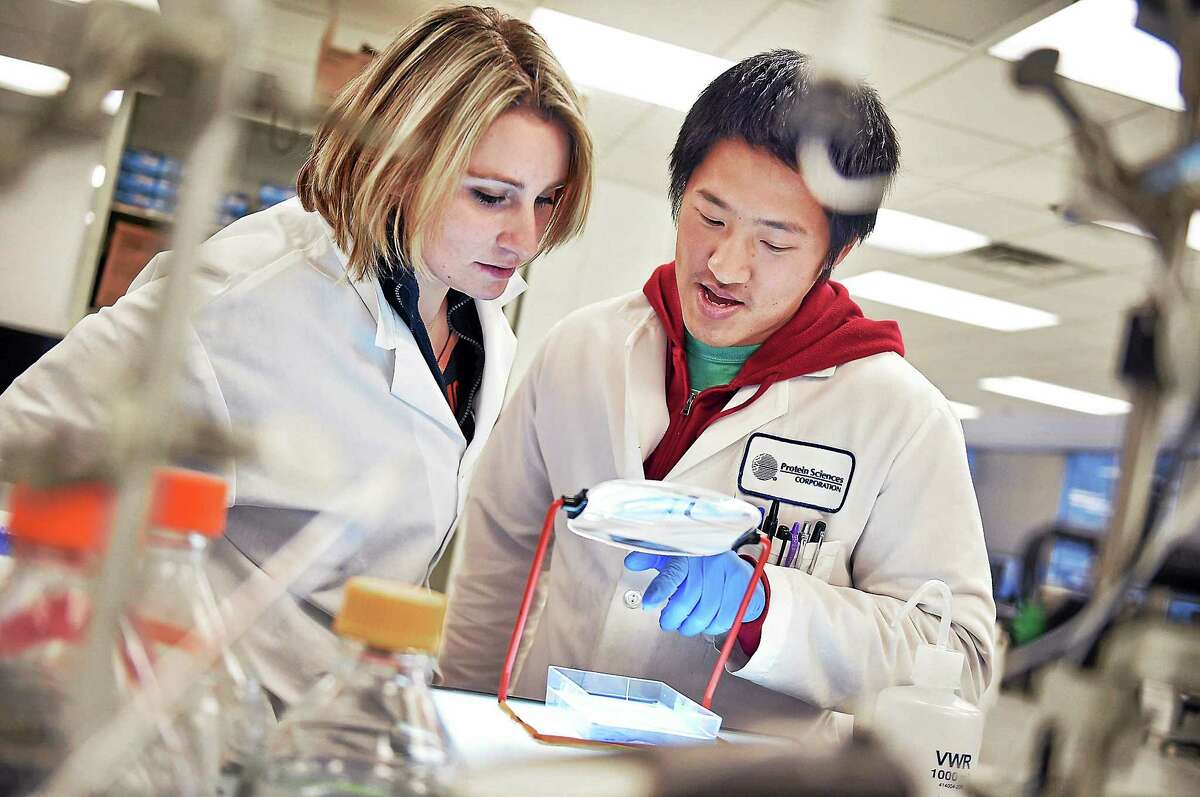 Scientist Guang Liu shows communications associate Courtney Goodwin the purity of an antigen in a FluBlok influenza vaccine at Protein Sciences at 1000 Research Pkwy in Meriden Wednesday, November 26, 2014.