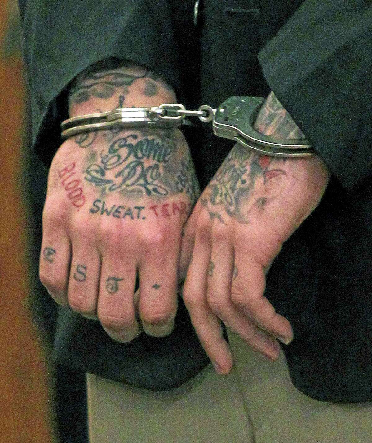 In this Dec. 23, 2013 file photo, former New England Patriots tight end Aaron Hernandez’s tattooed hands are secured with handcuffs as he arrives for his court appearance at Superior Court in Fall River, Massachusetts.