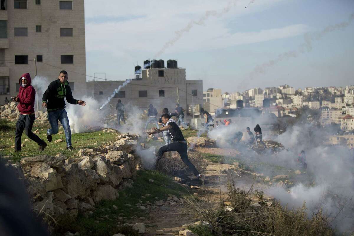 Palestinian protesters run from tear gas fired by Israeli troops during clashes outside Ofer military prison near the West Bank city of Ramallah, Friday, Nov. 27, 2015.