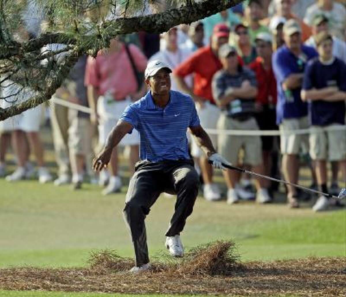 In this April 9, 2011, file photo, Tiger Woods nearly falls backward after hitting out of the rough under the Eisenhower Tree on the 17th hole during the third round of the Masters golf tournament in Augusta, Ga.