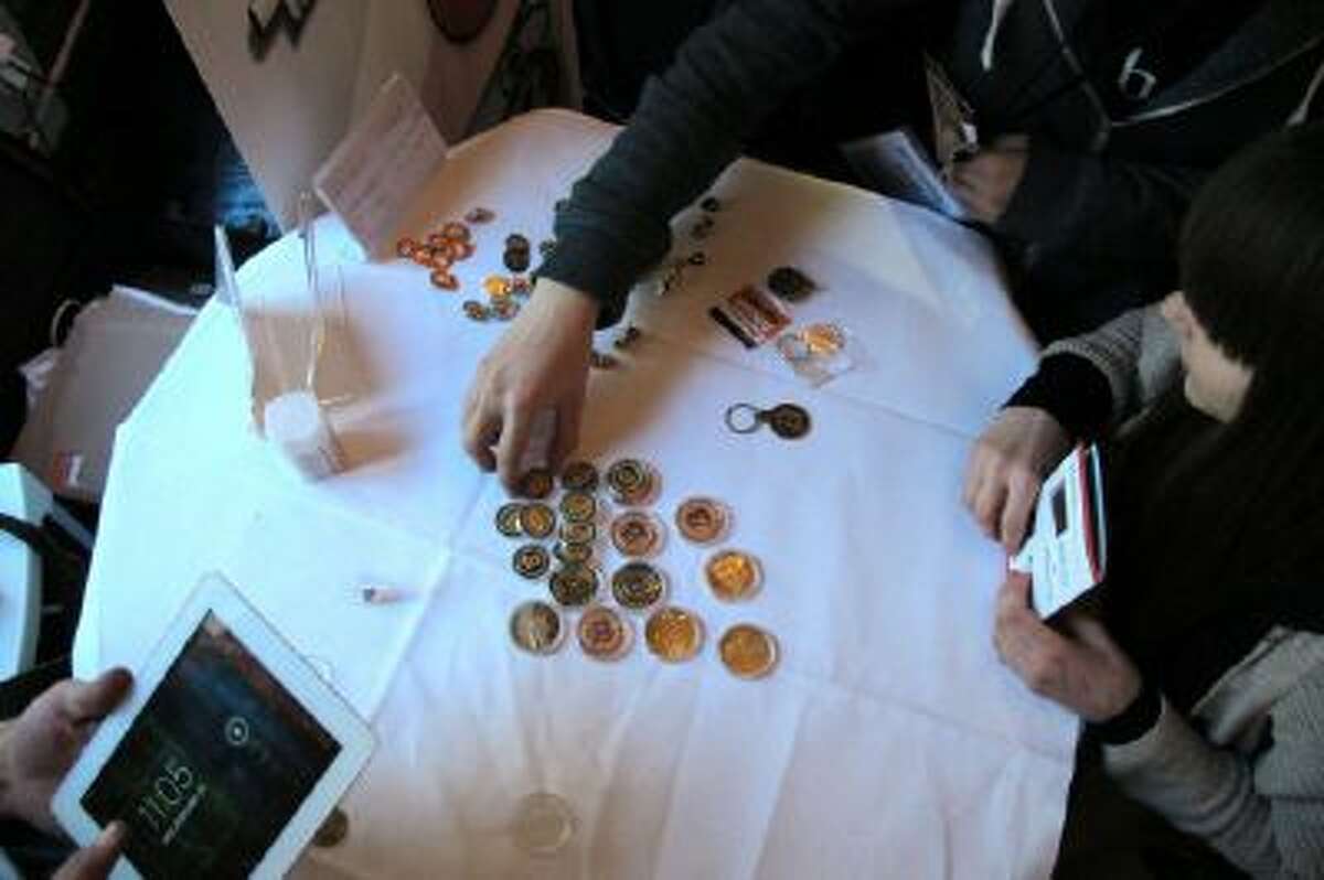 Attendees of the Inside Bitcoins conference in Berlin examine Bitcoin buttons on Wednesday, Feb. 12, 2014.