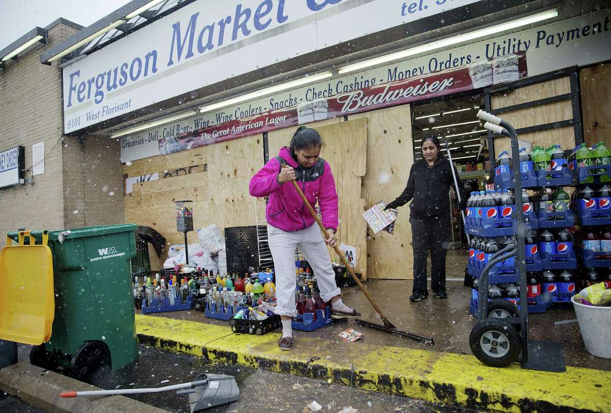 Anjana Patel cleans up the damage from Monday's riots at her store, Ferguson Market and Liquor, Wednesday, Nov. 26, 2014, in Ferguson, Mo. A grand jury's decision not to indict a police officer in the shooting death of an unarmed 18-year-old has stoked passions nationwide, triggering debates over the relations between black communities and law enforcement. (AP Photo/David Goldman)