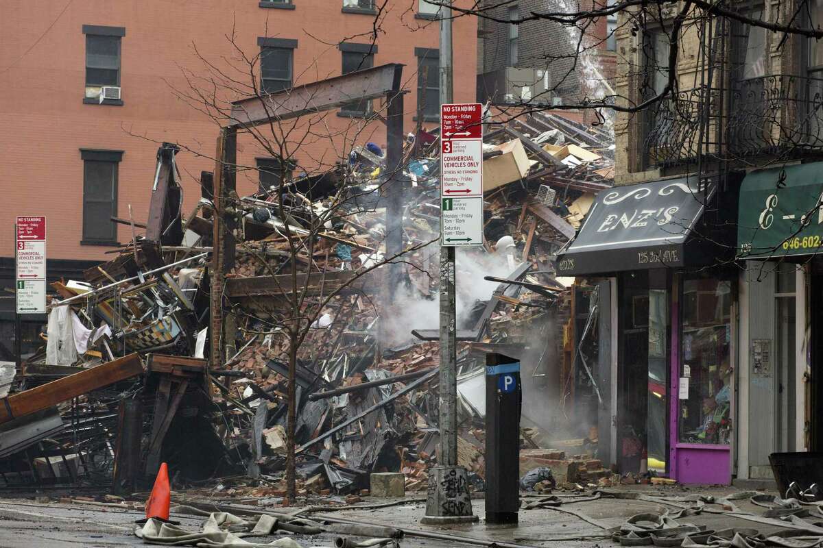 Debris from collapsed buildings smolders in the East Village neighborhood of New York, Friday, March 27, 2015. Authorities say two people are unaccounted for following an apparent gas explosion that leveled three buildings. Preliminary evidence suggested a gas explosion amid plumbing and gas work inside the building was to blame. (AP Photo/Mark Lennihan)