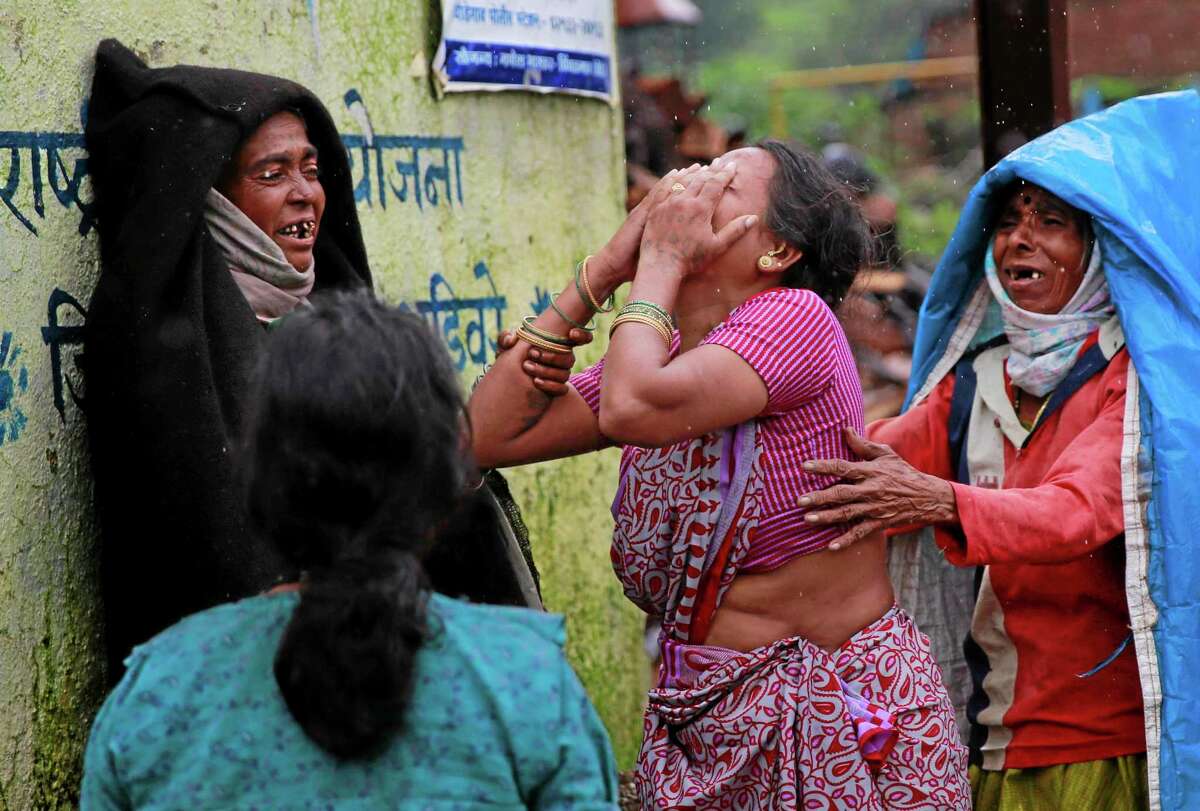 Relatives wail after seeing the body of a victim after a massive landslide in Malin village in Pune district of western Maharashtra state, India, Thursday, July 31, 2014. Two days of torrential rains triggered the landslide early Wednesday, killing more than two dozen people and trapping more than 150, authorities said. (AP Photo/Rafiq Maqbool)