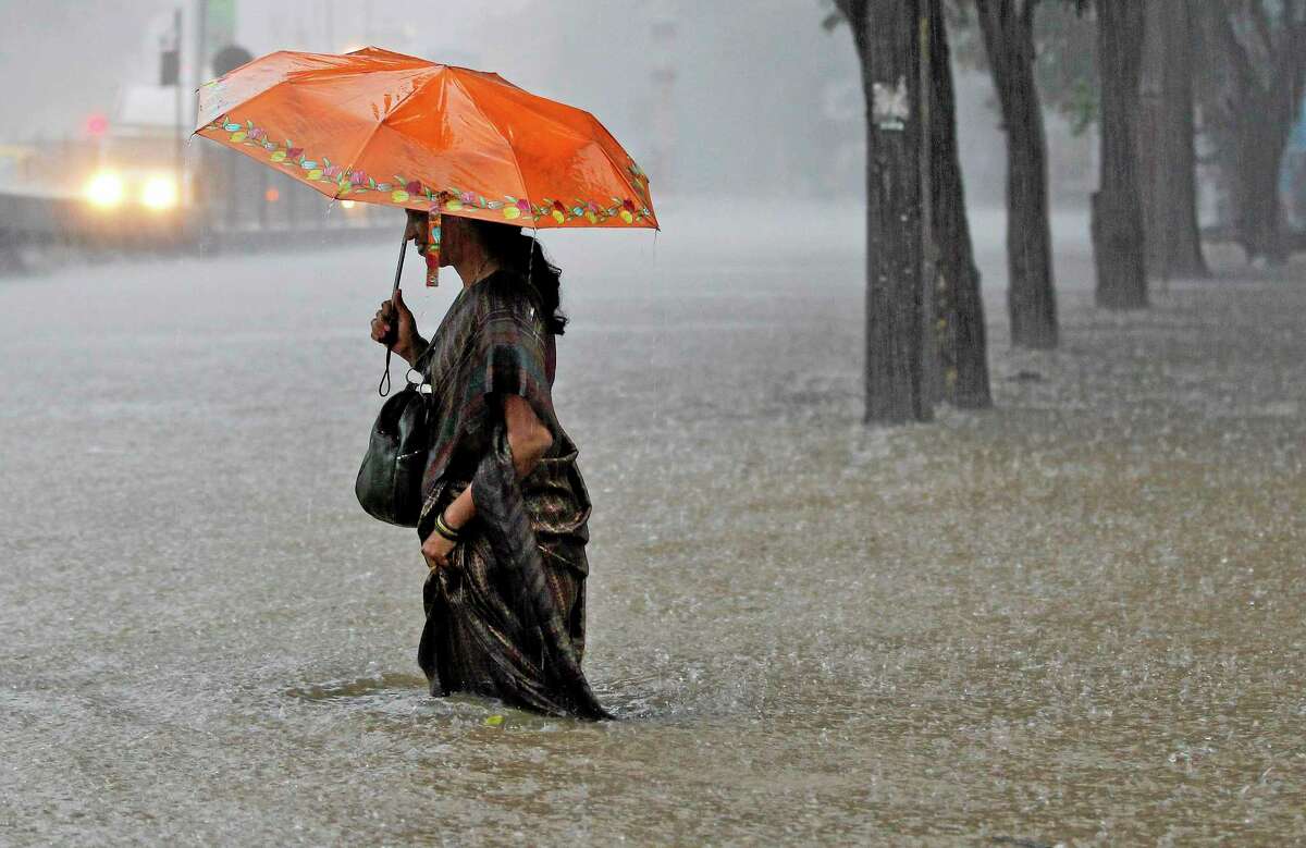 An Indian woman wades through a waterlogged street as it rains in Mumbai, India, Thursday, July 31, 2014. Heavy rainfall in the city flooded several areas causing traffic havoc and delay in trains. (AP Photo/Rajanish Kakade)