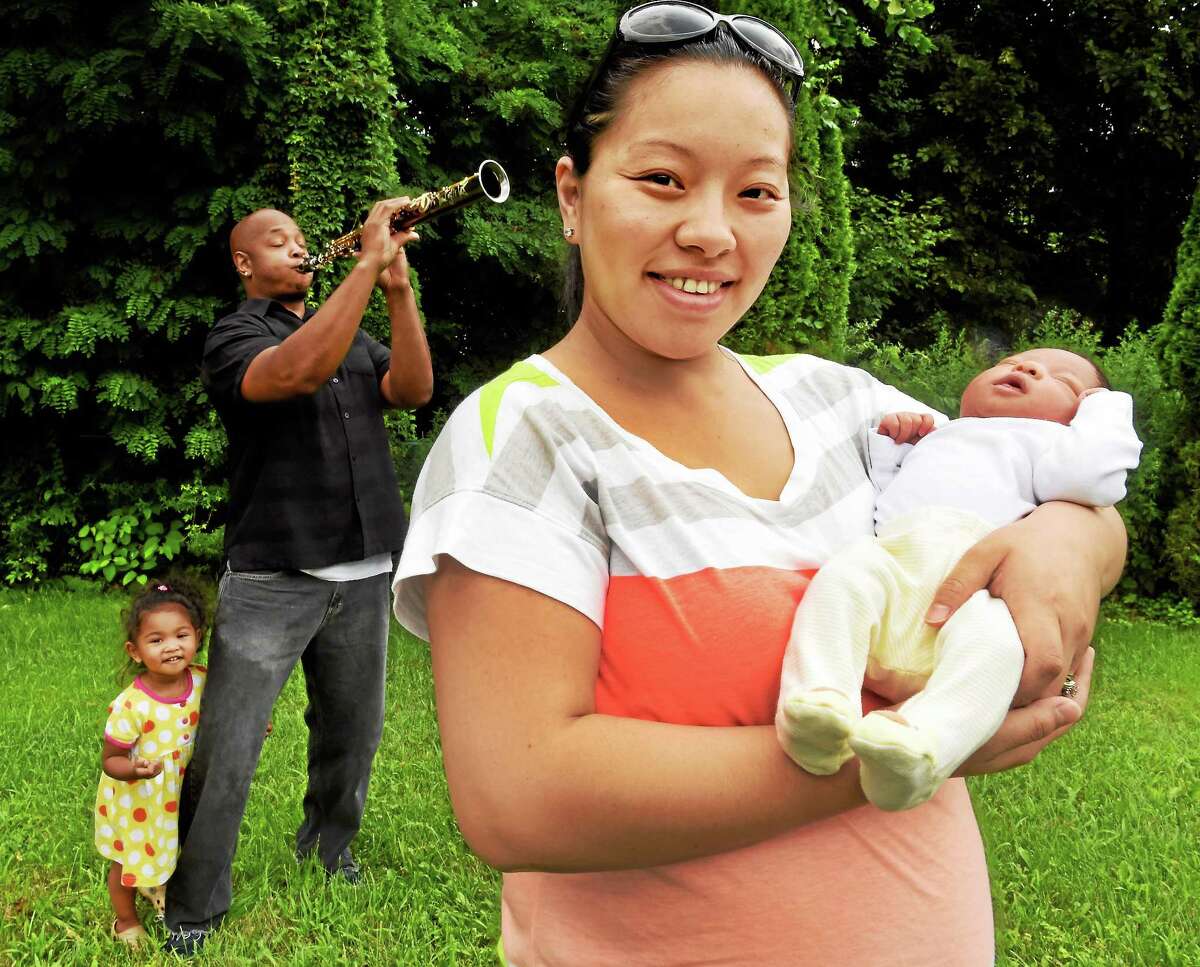 Lillie Davis shows off newborn Livia, just 4 days old, as father David Davis, a professional musician, lets loose with some celebratory sounds outside the family home in West Haven as daughter, 2, seems entertained by it all.