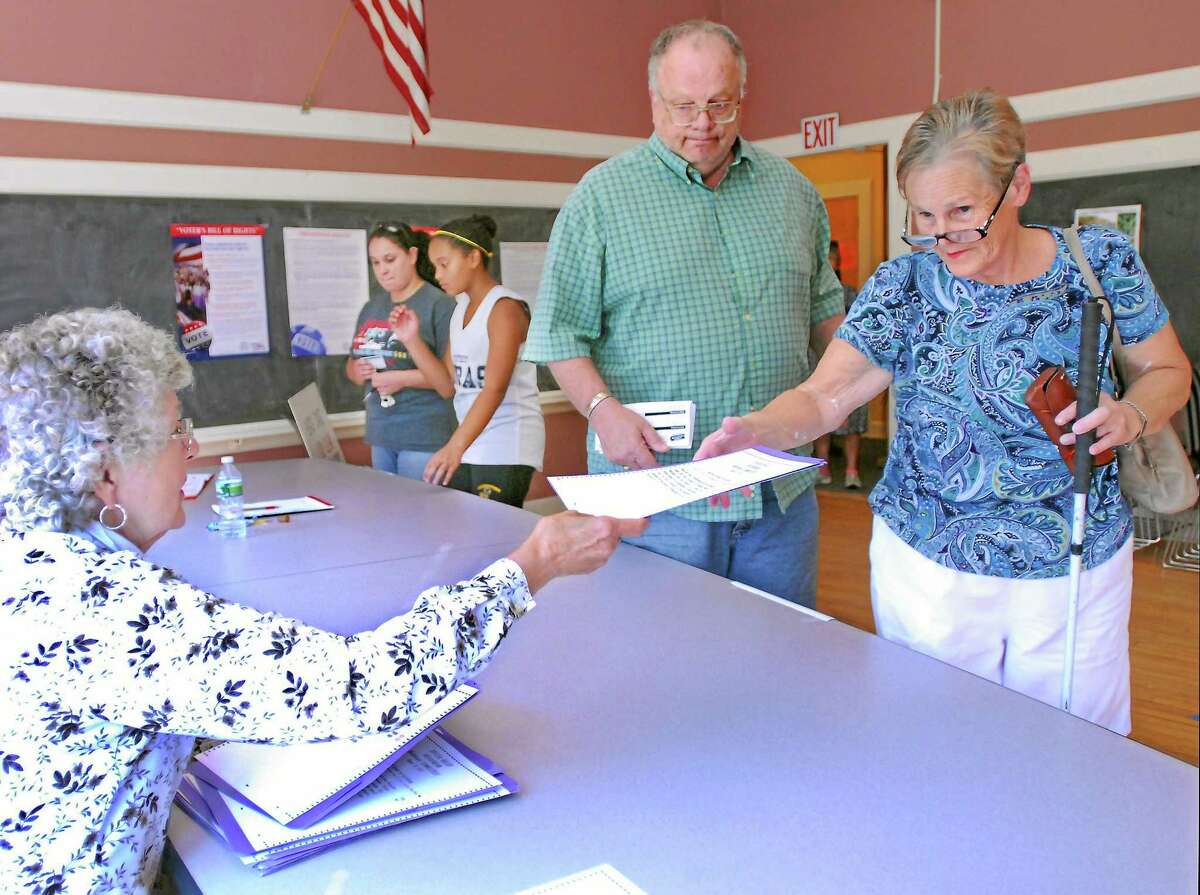Middlefield residents Kathy and Gerald Begin pick up a ballot from Sharlene Menard to vote for the sale of Powder Ridge to Sean Hayes in this August 2012 file photo.